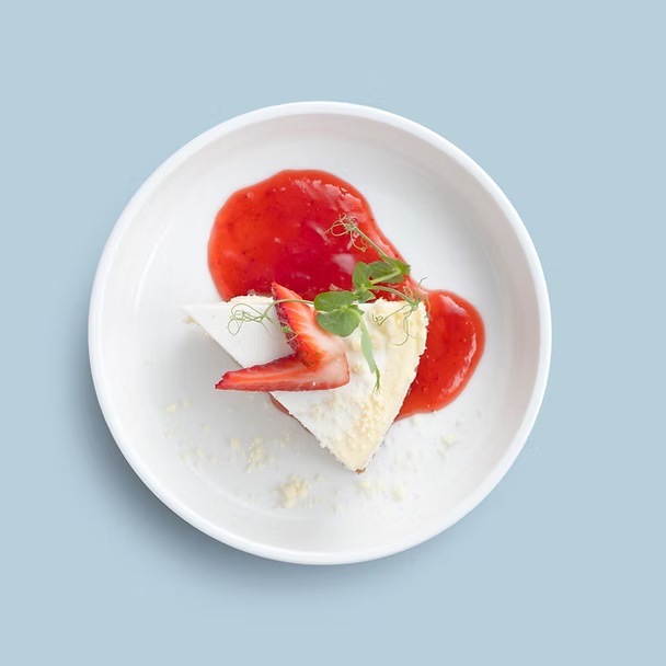 Classic cheesecake topped with raspberry jam & sliced strawberries